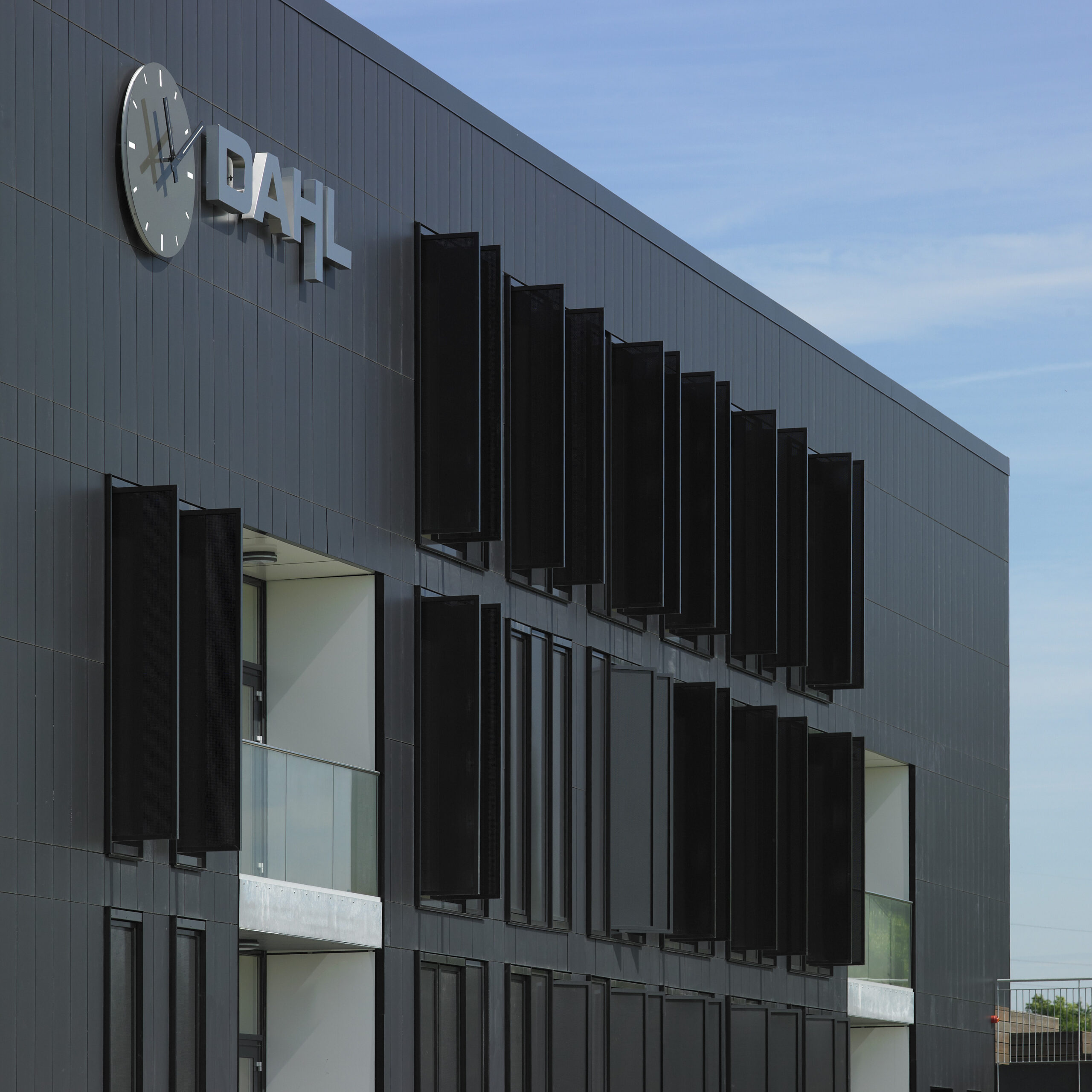 Seitenansicht der Anwaltskanzlei Dahl in Viborg mit modernen schwarzen Keramikpaneelen, vertikalen Fenstern und einem großen Uhrenschild