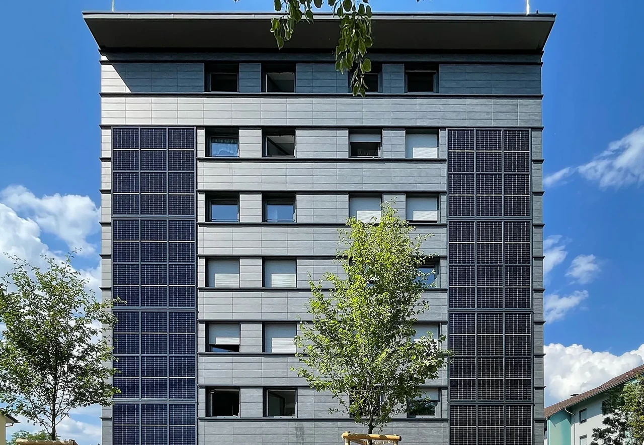 Frontansicht der sanierten Keramikfassade eines Gebäudes in Lindau mit grauen Platten und Solarpaneelen